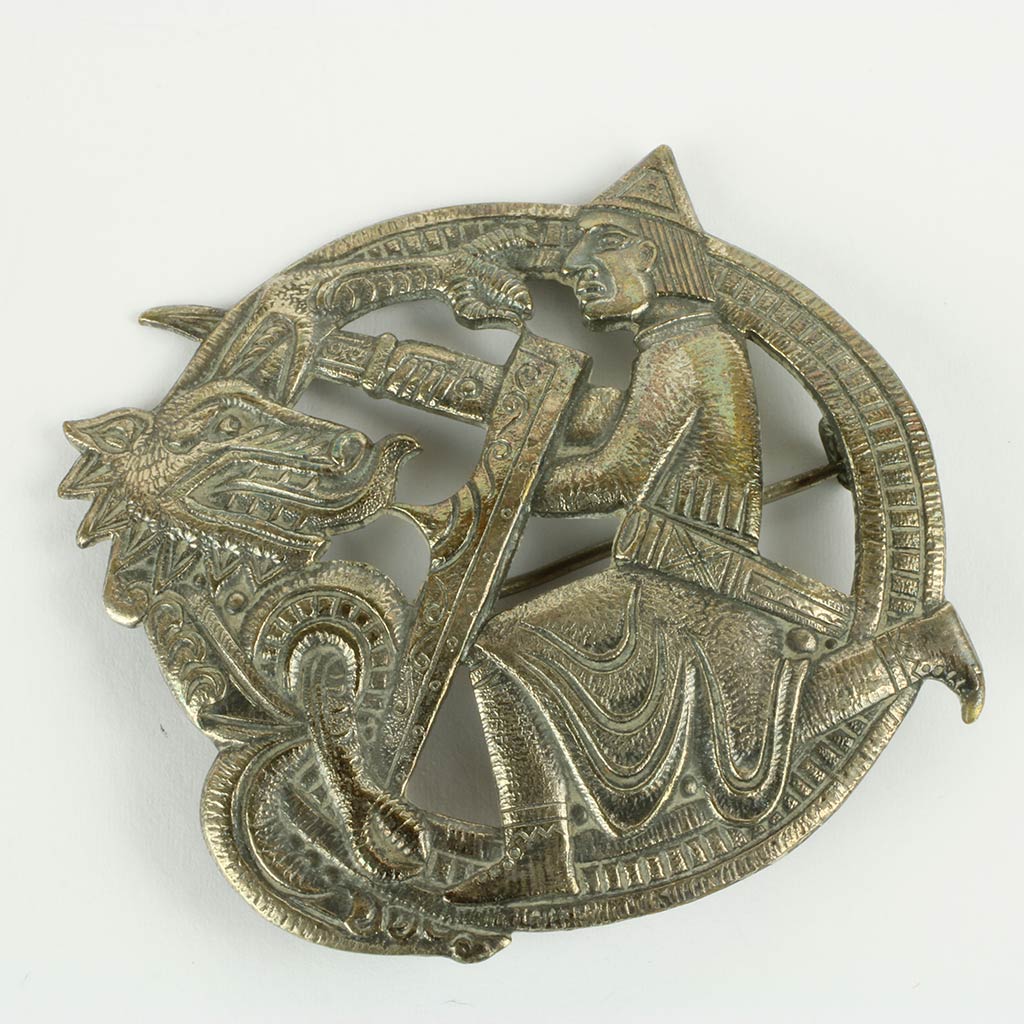 Broche af sølv lignende metal forestillende viking og drage