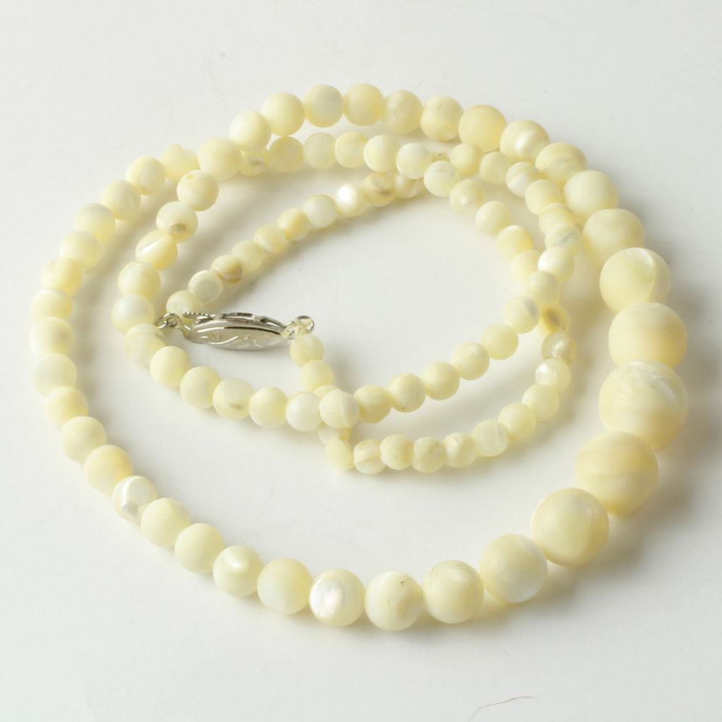 Lang halskæde af drejet perlemor med perler i forløb