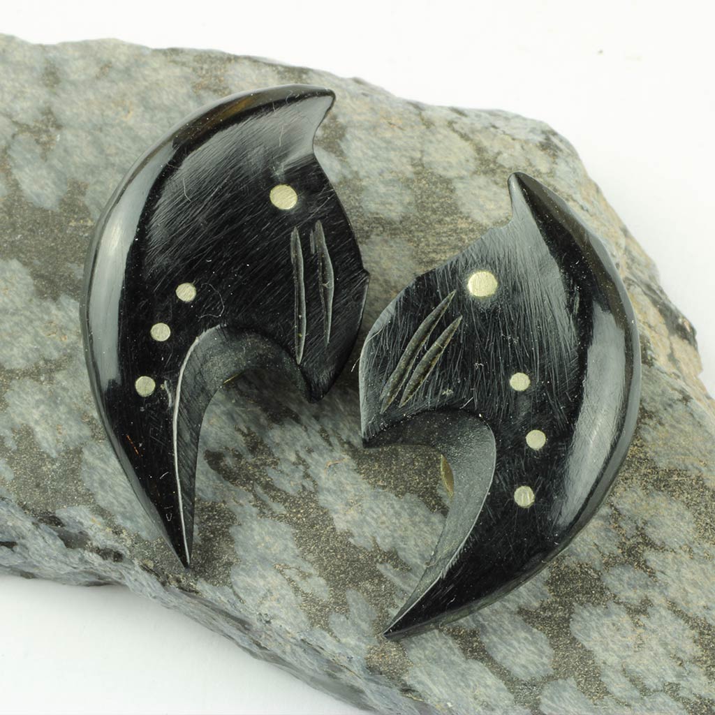 øreklips udskåret af sort horn med indlagt hvidt metal antagelig sølv